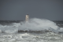 Faro di Mangiabarche avvolto dagli spruzzi del mare in burrasca