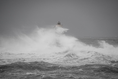 Faro di Mangiabarche avvolto dagli spruzzi del mare in burrasca