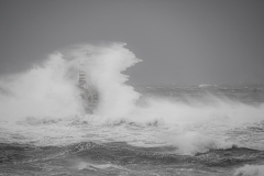 Faro di Mangiabarche avvolto dagli spruzzi del mare in burrasca