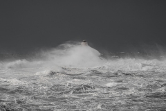 Faro di Mangiabarche avvolto dagli spruzzi del mare in burrasca