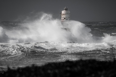 Faro di Mangiabarche avvolto dagli spruzzi del mare in burrasca