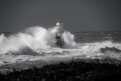 Faro di Mangiabarche avvolto dagli spruzzi del mare in burrasca