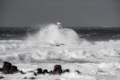 Faro di Mangiabarche avvolto dagli spruzzi del mare in burrasca