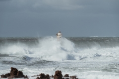 Faro di Mangiabarche avvolto dagli spruzzi del mare in burrasca
