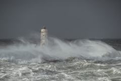 Faro di Mangiabarche avvolto dagli spruzzi del mare in burrasca