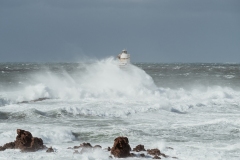 Faro di Mangiabarche avvolto dagli spruzzi del mare in burrasca