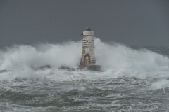 Faro di Mangiabarche avvolto dagli spruzzi del mare in burrasca