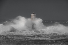 Faro di Mangiabarche avvolto dagli spruzzi del mare in burrasca