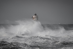 Faro di Mangiabarche avvolto dagli spruzzi del mare in burrasca