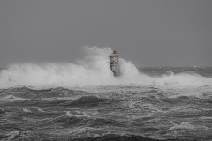 Faro di Mangiabarche avvolto dagli spruzzi del mare in burrasca