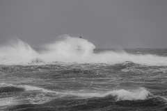 Faro di Mangiabarche avvolto dagli spruzzi del mare in burrasca