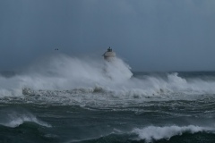 Powerful waves crashing against a Mangiabarche lighthouse during a hurricane, symbolizing resilience and the forces of nature