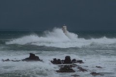 Powerful waves crashing against a Mangiabarche lighthouse during a hurricane, symbolizing resilience and the forces of nature