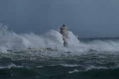 Powerful waves crashing against a Mangiabarche lighthouse during a hurricane, symbolizing resilience and the forces of nature