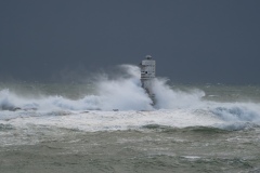 Powerful waves crashing against a Mangiabarche lighthouse during a hurricane, symbolizing resilience and the forces of nature