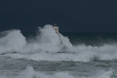 Powerful waves crashing against a Mangiabarche lighthouse during a hurricane, symbolizing resilience and the forces of nature