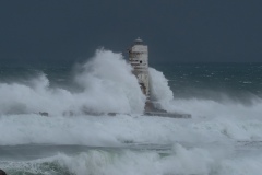 Powerful waves crashing against a Mangiabarche lighthouse during a hurricane, symbolizing resilience and the forces of nature