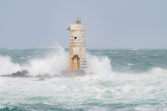 Powerful waves crashing against a Mangiabarche lighthouse during a hurricane, symbolizing resilience and the forces of nature