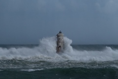 Powerful waves crashing against a Mangiabarche lighthouse during a hurricane, symbolizing resilience and the forces of nature