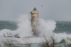 Powerful waves crashing against a Mangiabarche lighthouse during a hurricane, symbolizing resilience and the forces of nature