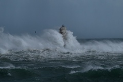 Powerful waves crashing against a Mangiabarche lighthouse during a hurricane, symbolizing resilience and the forces of nature