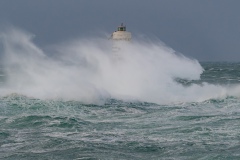 Powerful waves crashing against a Mangiabarche lighthouse during a hurricane, symbolizing resilience and the forces of nature