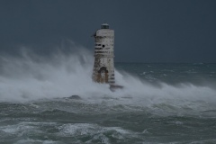 Powerful waves crashing against a Mangiabarche lighthouse during a hurricane, symbolizing resilience and the forces of nature