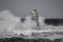 Faro di Mangiabarche avvolto dagli spruzzi del mare in burrasca
