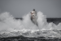 Faro di Mangiabarche avvolto dagli spruzzi del mare in burrasca