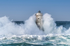 Faro di Mangiabarche avvolto dagli spruzzi del mare in burrasca
