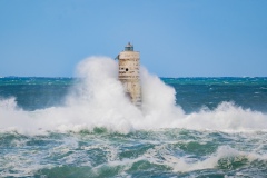 Faro di Mangiabarche avvolto dagli spruzzi del mare in burrasca
