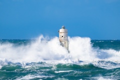 Faro di Mangiabarche avvolto dagli spruzzi del mare in burrasca