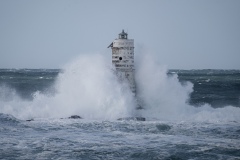Faro di Mangiabarche avvolto dagli spruzzi del mare in burrasca