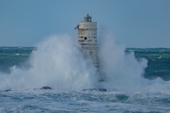 Faro di Mangiabarche avvolto dagli spruzzi del mare in burrasca