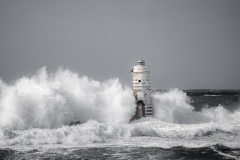 Faro di Mangiabarche avvolto dagli spruzzi del mare in burrasca
