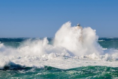 Faro di Mangiabarche avvolto dagli spruzzi del mare in burrasca