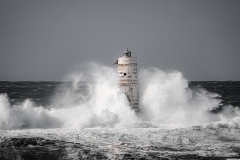 Faro di Mangiabarche avvolto dagli spruzzi del mare in burrasca