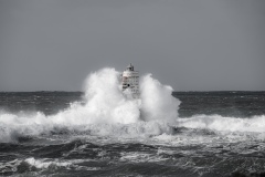 Faro di Mangiabarche avvolto dagli spruzzi del mare in burrasca