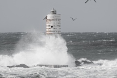 Faro di Mangiabarche avvolto dagli spruzzi del mare in burrasca
