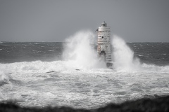 Faro di Mangiabarche avvolto dagli spruzzi del mare in burrasca