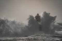 Faro di Mangiabarche avvolto dagli spruzzi del mare in burrasca